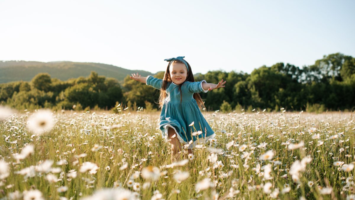 Funny kid girl in floral field outdoor