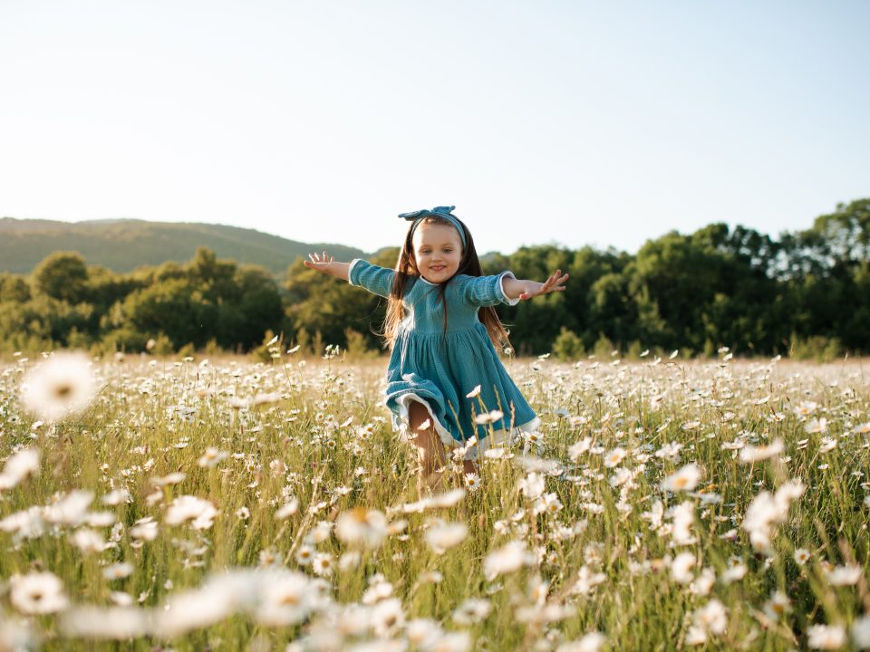 Funny kid girl in floral field outdoor